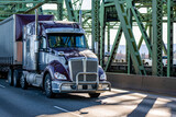 Fototapeta Mapy - Purple big rig bonnet semi truck with grey accents transporting cargo in dry van tarp semi trailer running on the truss arched bridge across the Columbia River