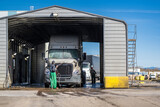 Fototapeta Mapy - Washers wash a big rig semi truck with trailer at an industrial wash for large vehicles
