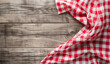 Red and White Gingham Cloth on Wooden Background. A red and white gingham cloth elegantly sprawls across a natural wooden plank background, invoking a rustic yet homely vibe.