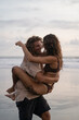 © Cavan Images - Young cheerful happy couple in love fooling around on the beach.