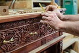 Fototapeta Desenie - person attaching brass handles to a carved mahogany drawer