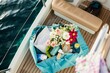 overhead shot of open bag with flowers and beach essentials on a yacht deck