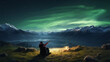 © Lustre Art Group  - Girl in a warm jacket sits on green grass in mountains near fire and admires northern lights and beautiful nature around her. Concept of happy holidays and rest, freedom, lifestyle. Ad