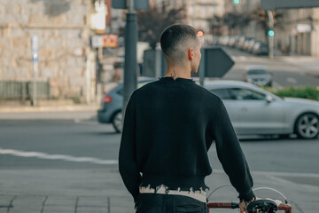 Wall Mural - young man walking on the street with bicycle on his back