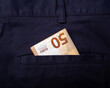 50 euro bill sticking out of the back pocket of dark blue pants, to pay in cash