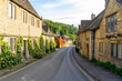 Scenic view of traditional old cottage houses and a street by a river in a beautiful English village, Castle Combe village in the Cotswolds Area of Outstanding Natural Beauty in Wiltshire, England.
