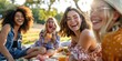 © kimly - A group of friends laughing together while enjoying a picnic in the park.
