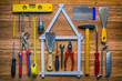 Sammlung von Werkzeugen auf Werkbank liegt um ein Haus geformt aus einem Zollstock