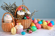 Easter holiday background. wicker basket with Easter cakes, colorful eggs and willow branches on table close up. Festive composition for Easter.