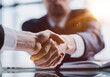 © Katsiaryna - Close-up high-angle view of unrecognizable business men handshaking after close deal and signed agreement at office over table paper contract.