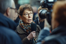 Mature Professional Politician Woman Giving An Interview For TV To A Reporter On The Street With A Microphone In Her Hand Talking To The Camera, Selective Focus
