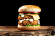 cheeseburger with chicken on a wooden board and a black background with a bright orange sauce