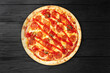 Bright pizza with tomato sauce on black wooden background top view