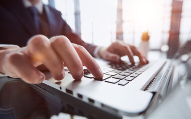 Wall Mural - Closeup image of a man working and typing on laptop computer keyboard