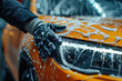 © Маргарита Вайс - Closeup of human hands in black rubber gloves washing a yellow car with foam and polish