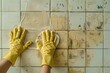 Young woman wearing rubber gloves cleaning a tiled wall in light ashy tones with sponge