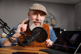Fototapeta Las - Studio podcast avec un micro et un ordinateur tablette et un homme souriant au look stylé et vintage avec une barbe hipster
