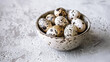 Fresh raw quail eggs of small spotted partridge or quail in a porcelain or ceramic bowl on a white table. Banner, card with place for text