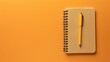 © Татьяна Макарова - A closed, brown notebook with a yellow pen on top, centered solid orange background.