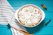 Cinnamon, homemade recipe of sweet traditional dessert buns with white cream sauce on blue wooden background