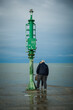 Senior couple kissing on the pier in a Riviera Romagnola beach location. Dramatic sky in a winter afternoon. Winter sea. Tenderness at old age.