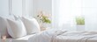 White linens cover a comfortable bed made of wood with matching pillows in a bedroom with hardwood flooring. A plant adds a touch of nature near the window