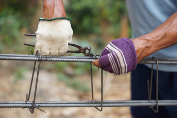 closeup construction worker ties iron wire on metal bar reinforcement of concrete work. concept, con