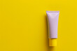 Modern cosmetic cream tube with a matte lavender finish against a bright yellow isolated solid background, creating a playful and fresh look,