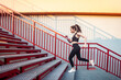 © khosrork - Full length portrait of slim athletic sporty woman wearing black sportswear doing physical exercising running on stairs training her body having cardio workout outdoor.