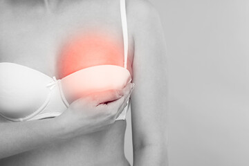 Canvas Print - Young woman suffering from breast pain on light grey background, closeup. Black and white with color accent effect