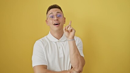 Wall Mural - Exciting moment when happy young hispanic man in glasses, gesturing the number one, has a brilliant idea, standing isolated on yellow background, his face beaming with clever success