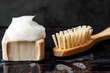 solid shampoo bar with foam on top beside a bamboo brush