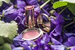 lipstick and compact mirror amid a bed of violets