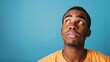 Puzzled African American man with confused expression, blue background portrait photograph