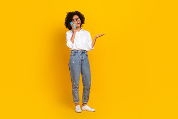 Wall Mural - Full length body size view of attractive cheerful girl talking on phone discussing news isolated over vivid yellow color background