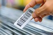 © Ilia Nesolenyi - A person holds a barcode in their hand, getting ready to affix it to a product as part of the inventory tracking process