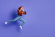© deagreez - Full length profile portrait of nice young woman jump fists fight empty space wear brown shirt isolated on purple color background