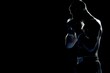 silhouette Angry MMA man fighter stand wearing boxing gloves on a black background