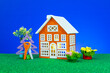 One orange house with flowers and a Christmas tree with keys around on a green surface