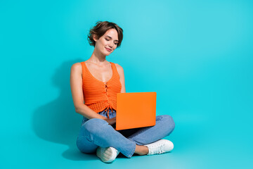 Poster - Full length photo of intelligent woman wear orange singlet sitting typing message on laptop isolated on turquoise color background