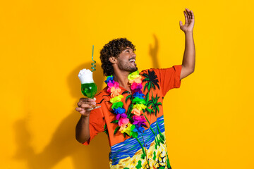 Portrait of positive cool guy wear hawaii shirt hold cocktail look at discount empty space isolated on vibrant yellow color background