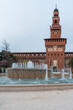 Main entrance to the Sforza Castle - Sforzesco castle and fountain in front of it, overcast day,Milan, Italy.