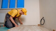 © DenisProduction.com - A worker is laying a new floor. Laying laminate in the house.