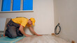 © DenisProduction.com - The master lays a new floor. Laying a wooden floor in a house.