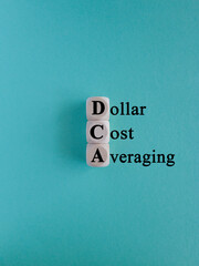 DCA (Dollar Cost Averaging) words on a wooden cubes. Blue background. Saving stock or savings on a monthly, quarterly basis.