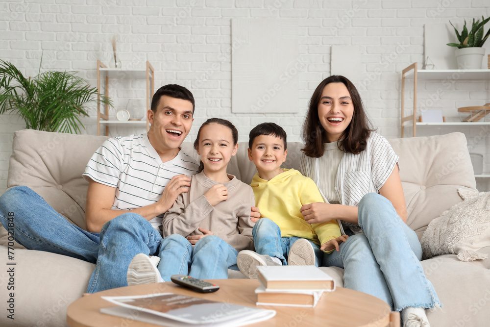 Happy family watching TV on sofa at home