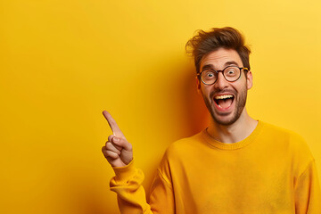 Ecstatic man in glasses and a yellow sweater pointing upwards, expressing a bright idea or sudden realization, against a yellow background