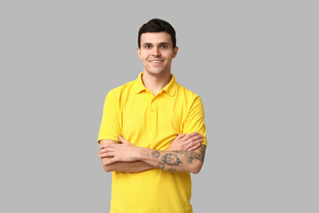 Sticker - Handsome young man in stylish yellow t-shirt on grey background