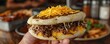 Medium shot of a Venezuelan arepa filled with cheese, beans, and shredded beef, held in hand