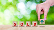 Realtor's hand puts cube with icon house and word SOLD. Concept of selling house, apartment, real estate. market of immobility, Property investment and house mortgage financial concept